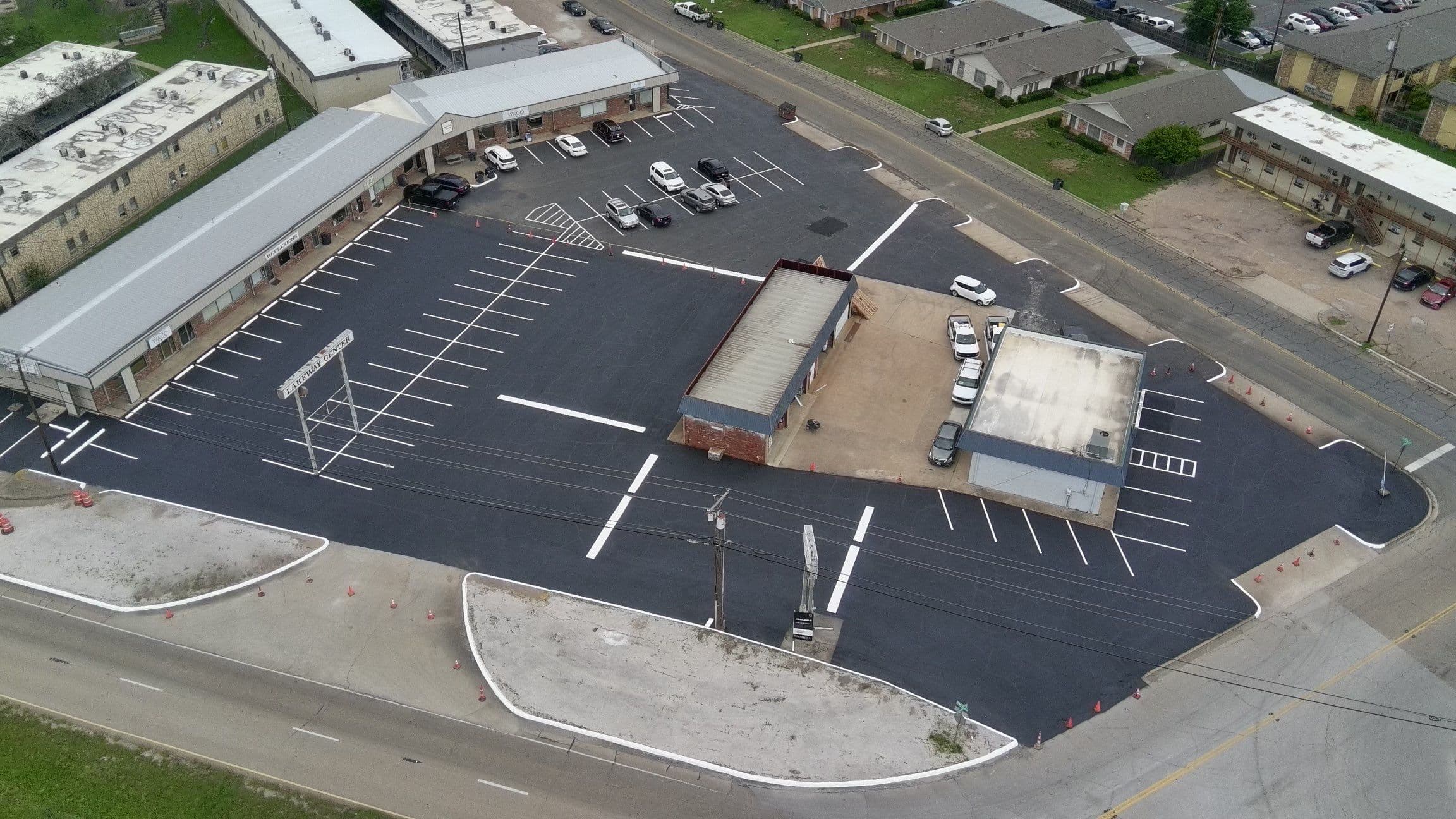 Aerial view of a freshly paved black asphalt parking lot with crisp white stripes.